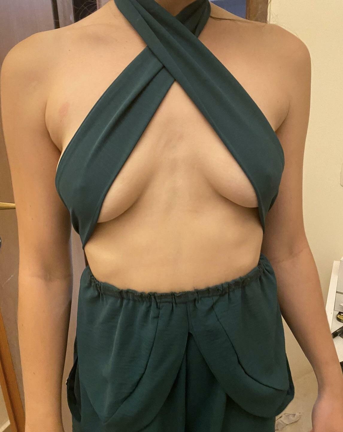 Mujer curvy de cabello negro posando frente al espejo en lencería verde oscuro cruzada